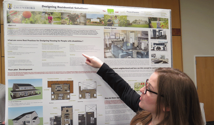 student pointing at research poster