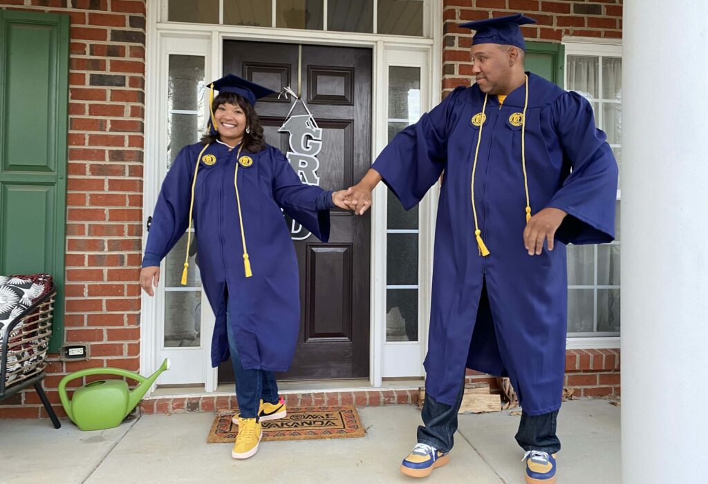 Woman and man in graduation cap and gown hold hands