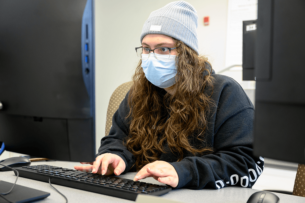 masked student sits at computer
