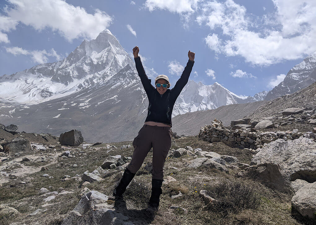 woman with arms up in front of mountain