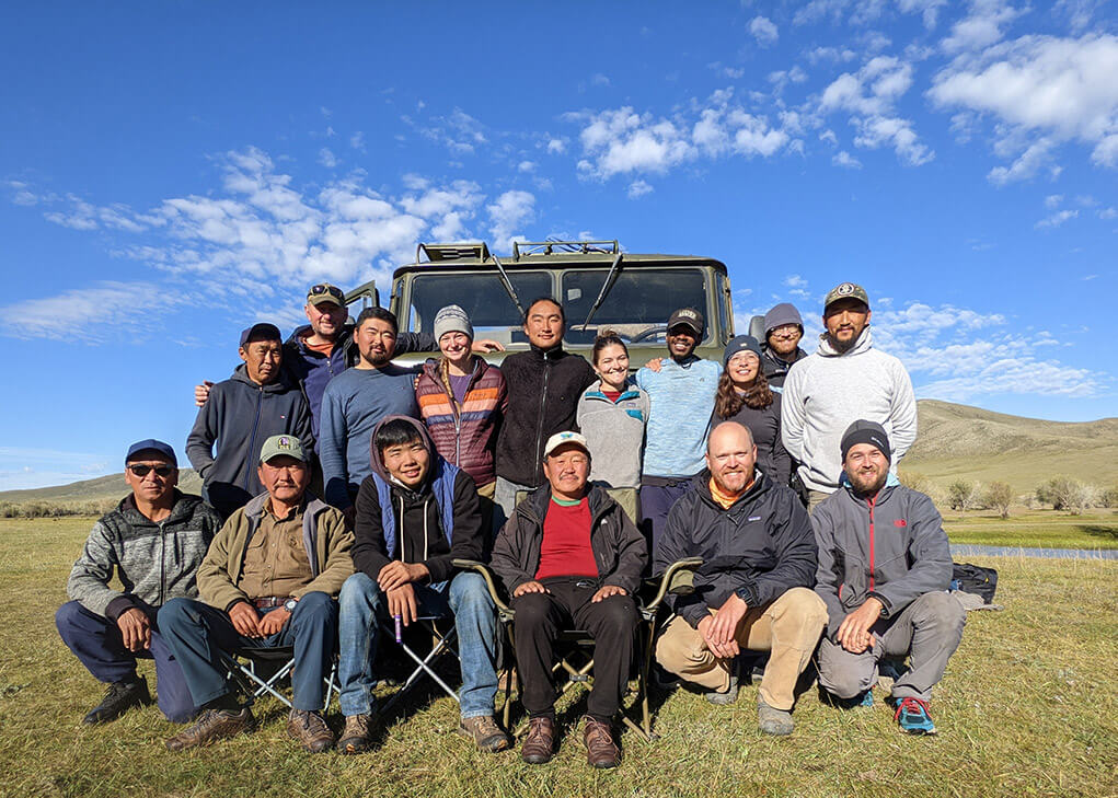 group of scientists and mongolians in front of vehicle