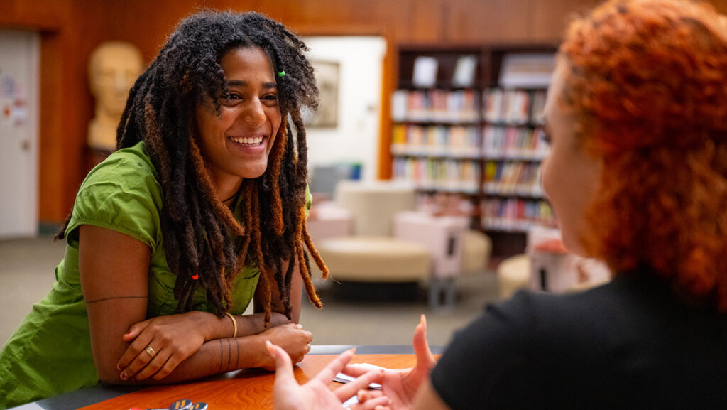Two women of color talk in a library