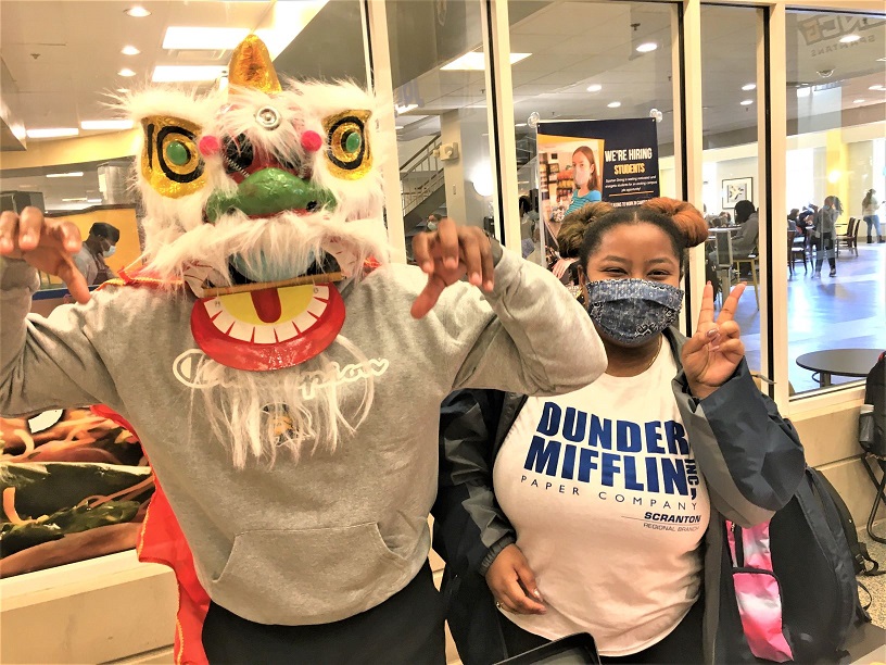 Two students at the Chinese Spring Festival, one wearing a dragon mask and the other holding up a peace sign
