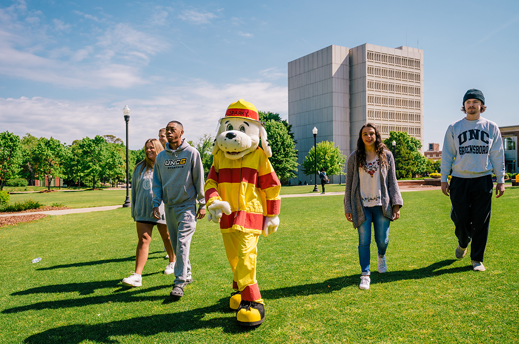 UNCG students walk on campus with fire department mascot, Sparky the dog