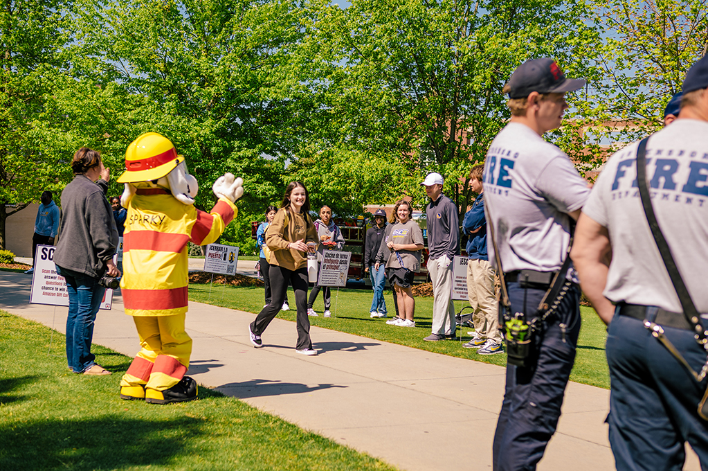 Group of students, firefighters, and mascot, Sparky on campus for fire safety walk.