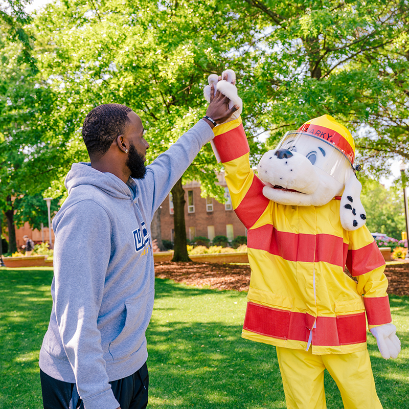 UNCG student gives a high-five to Sparky the Dog mascot.