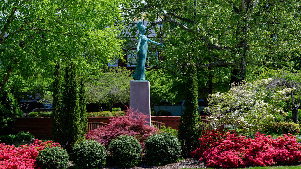 the minerva statue on a spring day, overlooking blooming hot pink azaleas
