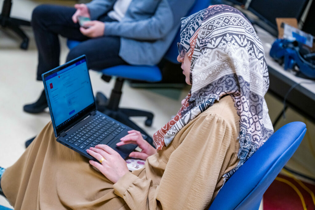 a woman in a head scarf types on her laptop