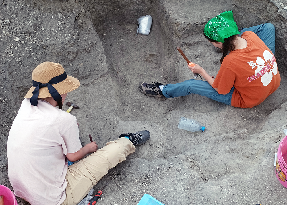 two students digging at archaeological site
