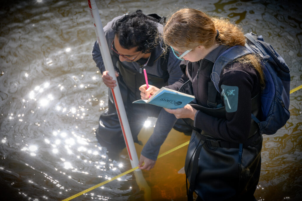 Two environmental students are conducting research within water