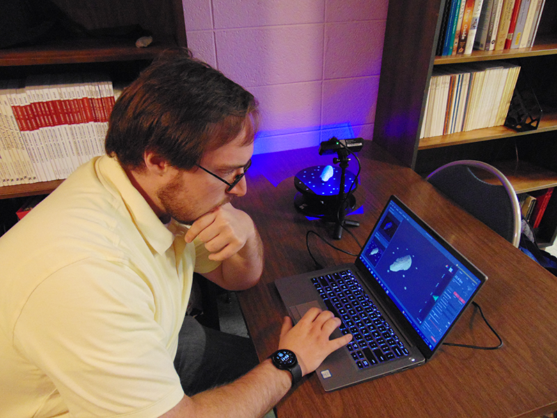 male student works on computer looking at artifacts