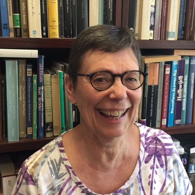 Dr. Denise Baker, smiling in front of a full bookcase