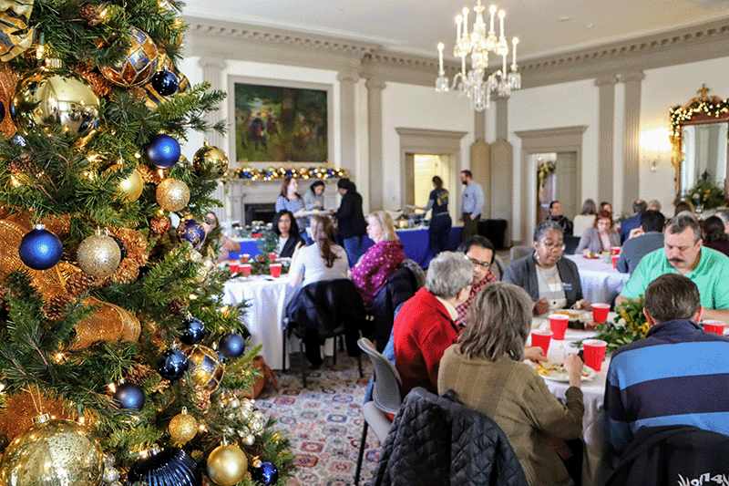 staff eating in alumni house with christmas tree in foreground