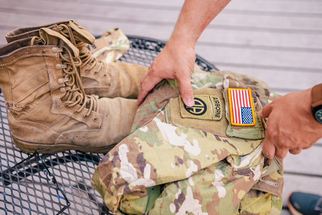 Hands reaching for Army uniform, folded next to Army boots