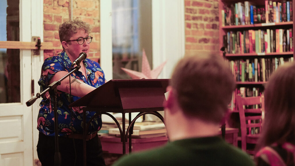 Emilia Phillips stands at podium at Scuppernong Books reading from poetry
