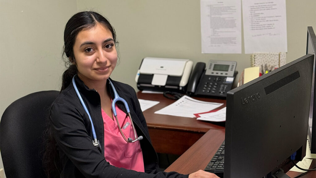 Caitlin Torres works at desk with stethoscope around neck