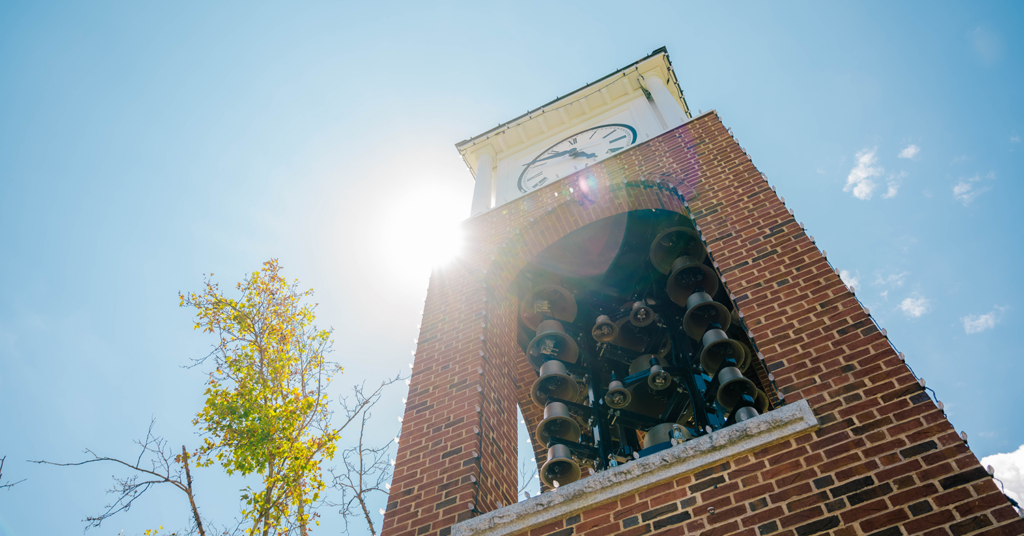 UNCG clocktower with sun peeking from behind