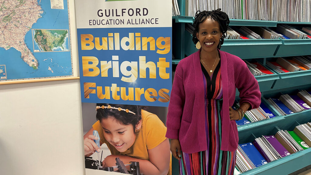 Alumna Dr. Zithobile “Zitty” Nxumalo ’11 stands in front of banner that says "Building Bright Futures" and shows a young girl studying