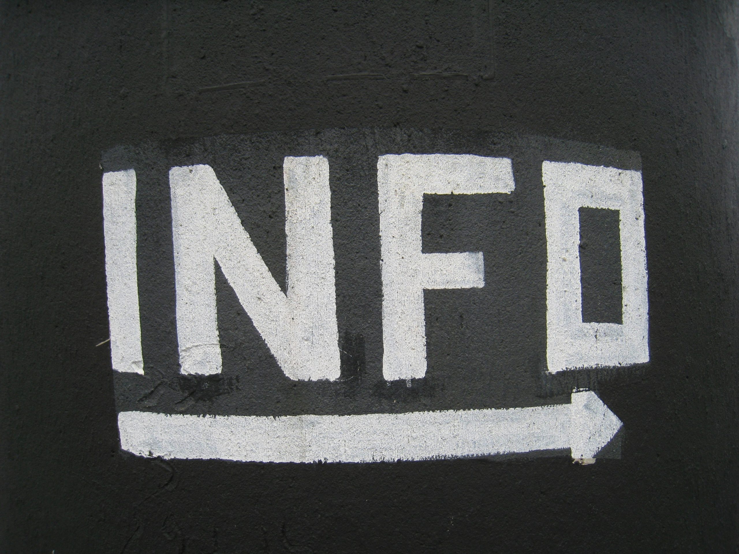 The word, INFO, painted on a black wall with white paint over a white painted arrow.