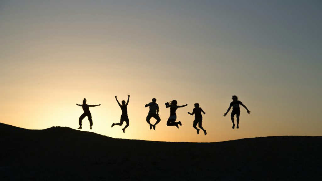 Silhouette of a group of people happily jumping in the air 