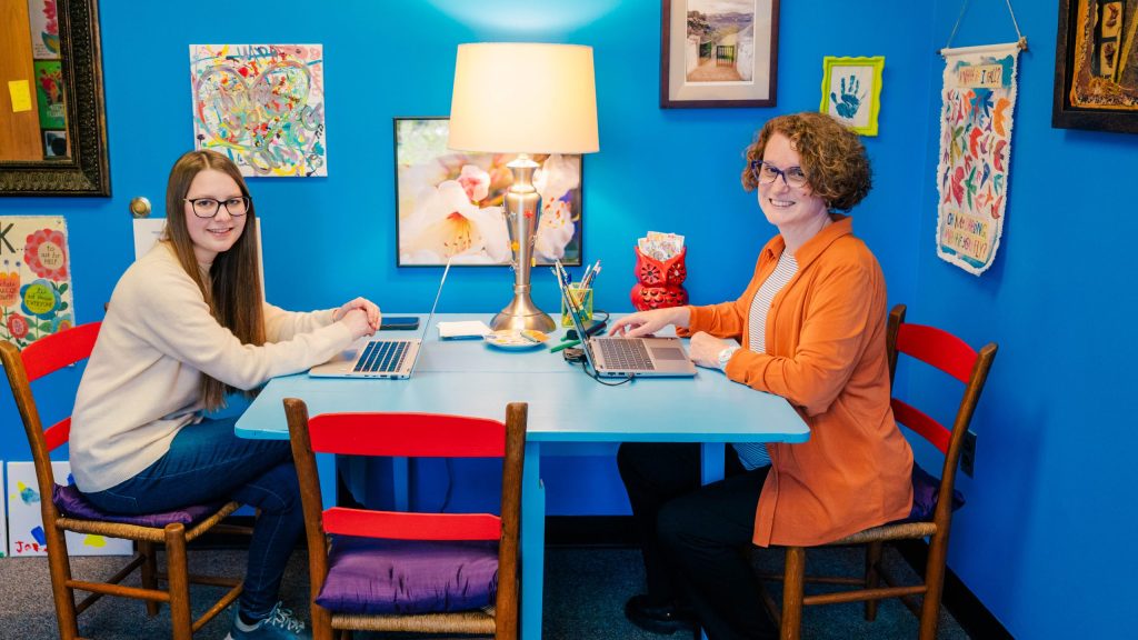 Kim Cuny sits with student at table