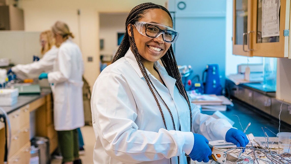 Janae Wofford in science lab with lab coat and safety goggles