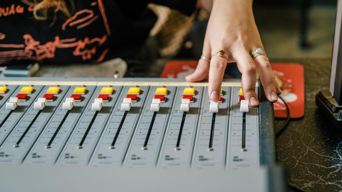 image of a hand on an audio mixing board