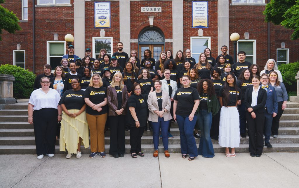 The Humanities at Work interns, faculty, and staff pose for a group photo outside on the steps of Curry Building.