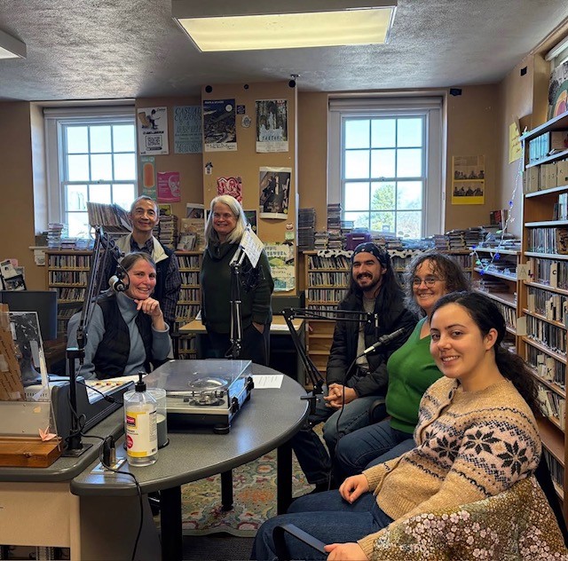 CAS deans, faculty, and students sit around the desk in the WUAG radio station during an episode of Research T at the G