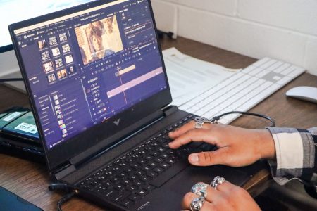 A closeup shot of Cole's hands and the laptop screen as he edits video footage.