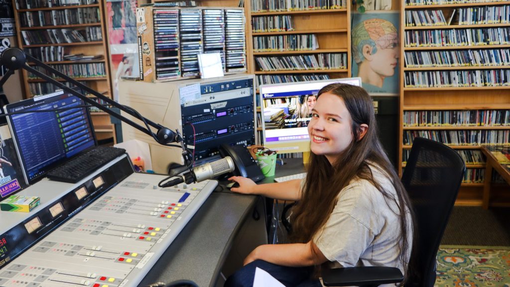 WUAG general manager Georgia Mrozkowski sits smiling behind the radio control board.