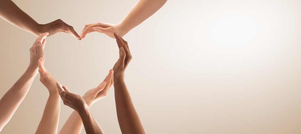 a diverse group of human hands reaching out to form a heart shape.