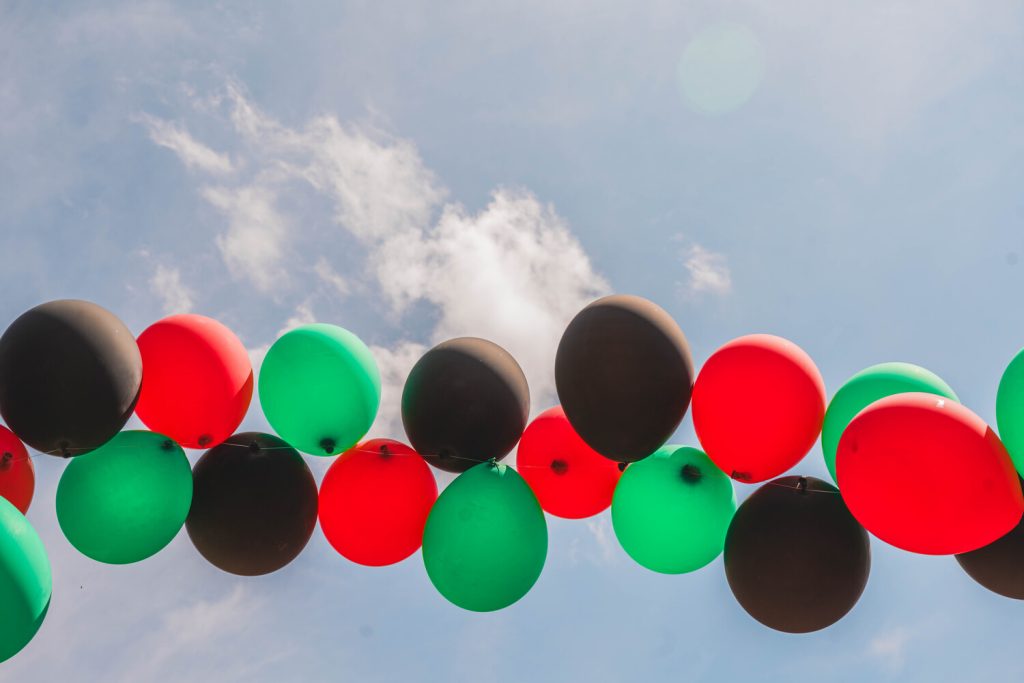 a string of red, black, and green balloons