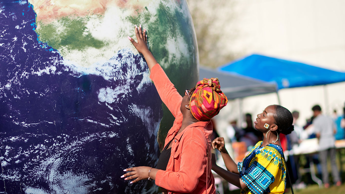 two people reaching up towards the African continent on a large globe