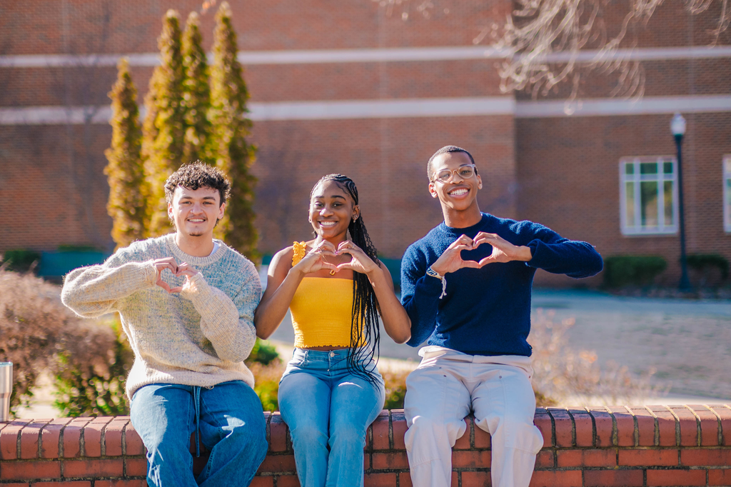 students smiling and making a heart shape with their hands