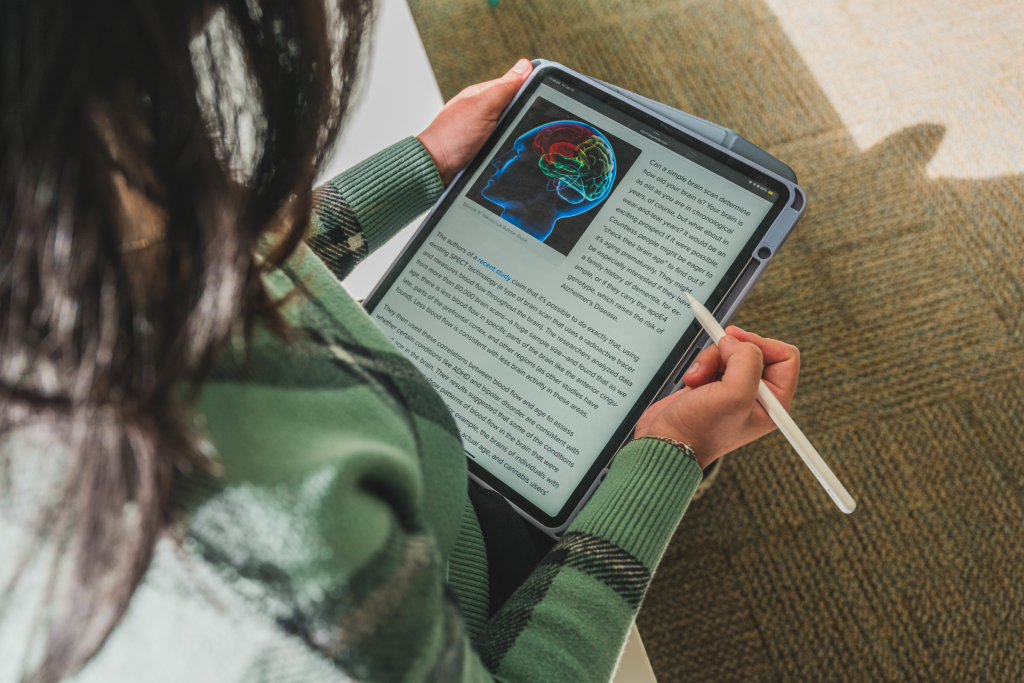 student holding a tablet with information about the human brain on display.