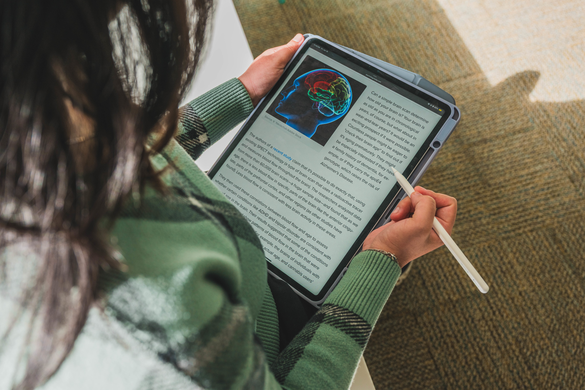 student holding a tablet with information about the human brain on display.